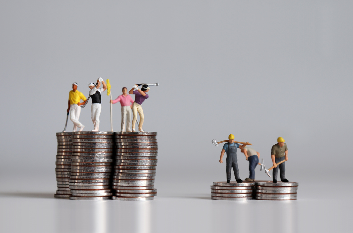 Concept of the gap between rich and poor. Miniature people standing on a pile of coins.